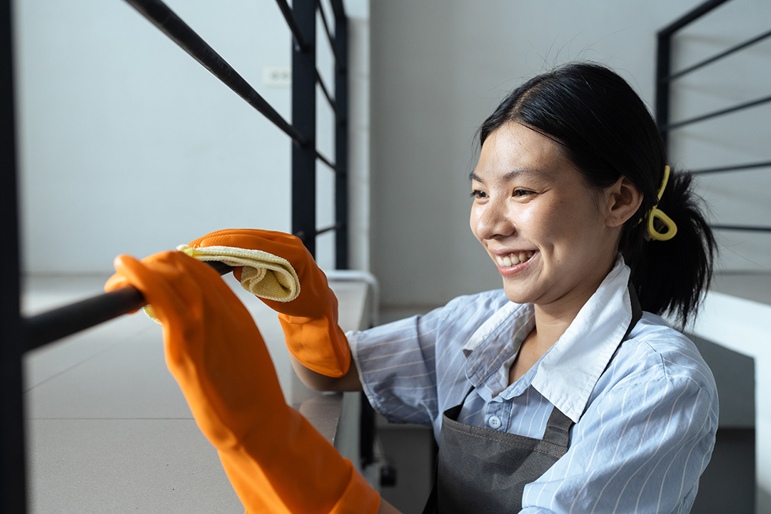 Hands in blue rubber gloves holding microfiber cleaning cloth make cleaning and disinfection for good hygiene of a stair railing